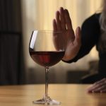 woman saying no to a glass of wine because of the link between alcohol and cancer