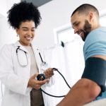 a male patient getting their blood pressure checked by a primary care physician